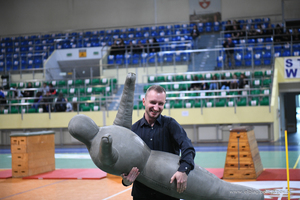 Hala sportowa. Mężczyzna niesie fantoma uzywanego do zajęć treningowych przez policjatów.