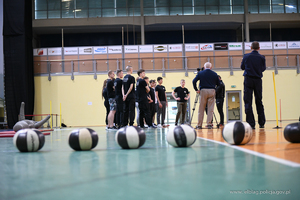 Policyjny instruktor w stroju sportowym tłumaczy kilku osobom zasady panujące na torze sprawnościowym