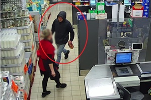Na ujęciu z kamery monitoringu widać mężczyznę ubranego w ciemną kurtkę, z butelką alkoholu w ręku. Po jego lewej stronie stoi ekspedientka, ubrana w czerwoną koszulkę.