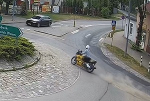 Na zdjęciu widać motocyklistę przejeżdżającego przez rondo a z nim podąża policyjny radiowóz na sygnałach