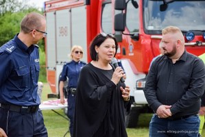 Trzy osoby w kadrze. Po lewej stronie umundurowany policjant. To Komendant Miejski Policji w Elblągu inspektor Robert Muraszko, po środku stoi kobieta to Burmistrz miasta i gminy Młynary Renata Wioletta Bednarczyk, po prawej stronie stoi mężczyzna w czarnej koszuli to Mateusz Zabłocki przedstawiciel podsekretarza stanu w Ministerstwie Aktywów Państwowych Andrzeja Śliwki.