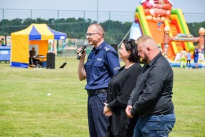 Trzy osoby w kadrze. Po lewej stronie umundurowany policjant. To Komendant Miejski Policji w Elblągu inspektor Robert Muraszko, po środku stoi kobieta to Burmistrz miasta i gminy Młynary Renata Wioletta Bednarczyk, po prawej stronie stoi mężczyzna w czarnej koszuli to przedstawiciel podsekretarza stanu w Ministerstwie Aktywów Państwowych Andrzeja Śliwki.