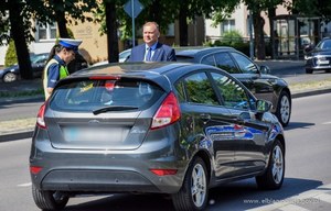 Samochód stoi na ulicy. Obok policjantka i mężczyzna w garniturze to Michał Missan wiceprezydentem Elbląga.