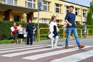 Umundurowana policjantka stoi przy przejściu dla pieszych szkoły podstawowej w Elblągu.