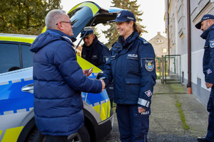 Umundurowana policjantka przyjmuje od mężczyzny w granatowej kurtce kluczyki od radiowozu.