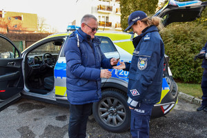 Umundurowana policjantka przyjmuje od mężczyzny w granatowej kurtce kluczyki od radiowozu.