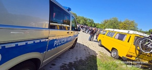 Z lewej strony policyjny radiowóz z prawej strony żółty bus na zlocie klasyków motoryzacji.