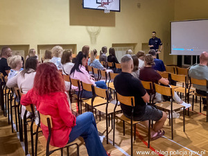 umundurowany policjant na sali gimnastycznej wypełnionej dziećmi i rodzicami