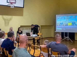 umundurowany policjant na sali gimnastycznej wypełnionej dziećmi i rodzicami