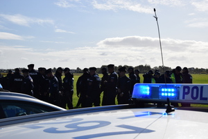 dach oznakowanego samochodu w tle umundurowani policjanci